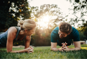 Sommer Marketing Ideen für Deine App - myFitApp Marketing Automation und @home Workout als Ideen. Ein Mann und eine Frau im Unterarmstütz im Park und lächeln.