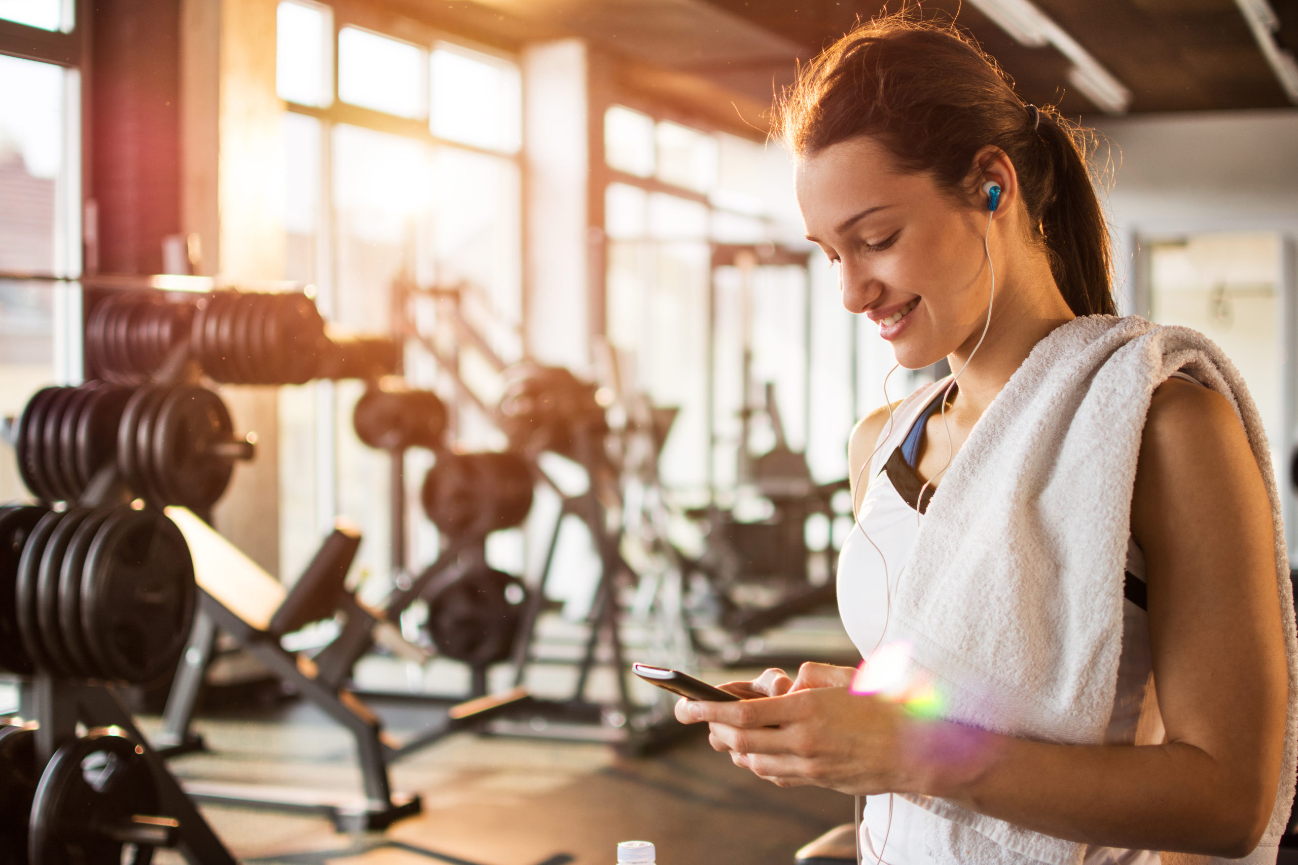 Active girl using smartphone in fitness gym.